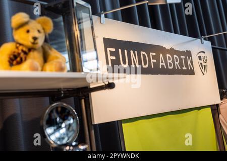 05. Mai 2023, Baden-Württemberg, Freiburg: Ein Schild mit der Aufschrift "Fundfabrik" hängt auf dem Stand der Abfallwirtschaft und Stadtreinigung Freiburg GmbH (ASF) auf der Nachhaltigkeits-Messe "Greenflair". Im nächsten Jahr soll der neue Second-Hand-Laden Fundfabrik der ASF eröffnet werden. Das Konzept ist „einzigartig“, neben einer ausgewählten Auswahl an gebrauchten Möbeln, Möbeln, Haushaltsartikeln und gebrauchter Bekleidung bietet die Fundfabrik ihren Gästen auch „Upcycling-Workshops“, einen „Reparaturworkshop“ und Bildungsmöglichkeiten zu den Themen Nachhaltigkeit und Kreislaufwirtschaft an. Die neue Bui Stockfoto