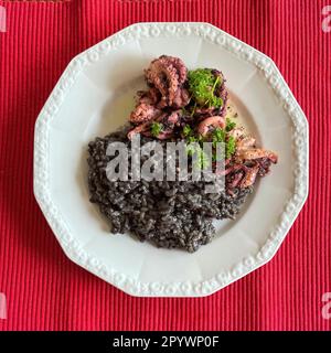 Italienisches Gericht der italienischen Küche Schwarzes Risotto nero mit Tintenfisch garniert mit Petersilie, Italien Stockfoto