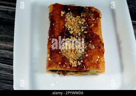 Apfelkuchen gefüllt mit cremigem Apfel, Zimt und süßem Honigsirup und garniert mit Pistazien und Nüssen, köstlicher süßer gebackener Apfelkuchen Stockfoto