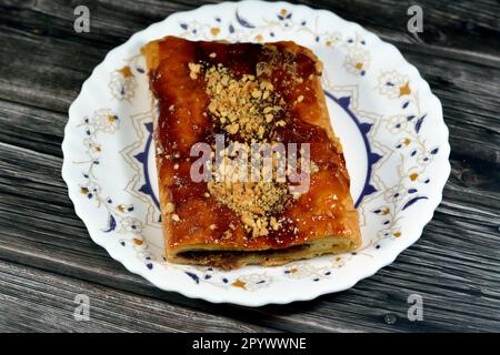 Apfelkuchen gefüllt mit cremigem Apfel, Zimt und süßem Honigsirup und garniert mit Pistazien und Nüssen, köstlicher süßer gebackener Apfelkuchen Stockfoto