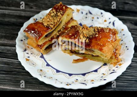 Apfelkuchen gefüllt mit cremigem Apfel, Zimt und süßem Honigsirup und garniert mit Pistazien und Nüssen, köstlicher süßer gebackener Apfelkuchen Stockfoto