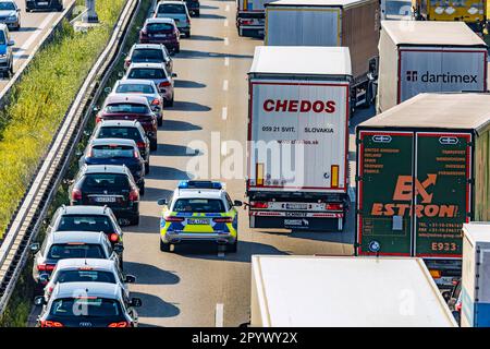 Polizeifahrzeug, das auf einer Notspur fährt, starker Verkehr mit Stau, Lastwagen und Autos auf der Autobahn A8 bei Stuttgart Stockfoto