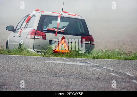 Ein Auto auf einer Wiese, ein Unfall mit Warndreieck, Bremsspuren zeigen, dass das Fahrzeug die Landstraße Rheinmünster, Baden-Württemberg verlassen hat Stockfoto