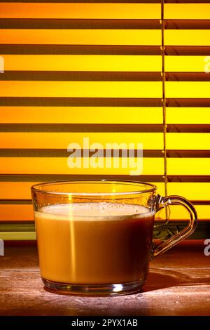 Glas-Kaffeetasse gefüllt mit Kaffee Set vor einem Küchenfenster-Jalousien Stockfoto