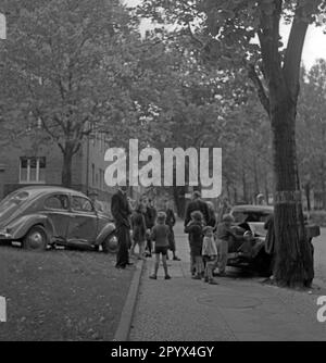 Undatiertes Foto eines Autounfalls mit zwei Autos auf einer Straße in Westberlin. Links ein verbeulter VW-Käfer neben einem unbekannten Auto. Die Fahrzeuge sind von Zuschauern umgeben, darunter Kinder, Erwachsene und Radfahrer. Stockfoto