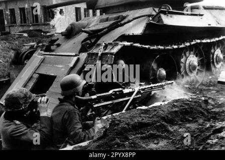 Deutsche Soldaten mit Maschinengewehr MG 34 in Stellung in Voronezh. Sie errichteten einen Unterschlupf unter der heruntergekommenen T34. Foto: Müller-Schwannecke [maschinelle Übersetzung] Stockfoto