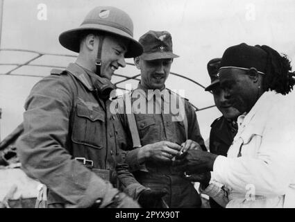 Soldaten der Armee des deutschen Afrika-Korps, die mit einem Einheimischen sprechen. Foto: Boecker. [Maschinelle Übersetzung] Stockfoto