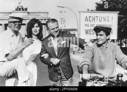 Amerikanischer Regisseur Billy Wilder, Schauspielerin Pamela Tiffin und Schauspieler James Cagney und Horst Buchholz (von links) vor dem Brandenburger Tor in Berlin während der Dreharbeiten des Films eins, zwei, drei. [Maschinelle Übersetzung] Stockfoto