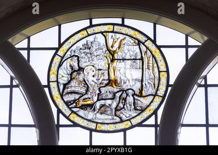 Innenseite der St. Hubert's Church, Idsworth, Hampshire, England, Großbritannien. Buntglasrunde im Ostfenster mit St. Hubert und dem Hirsch Stockfoto