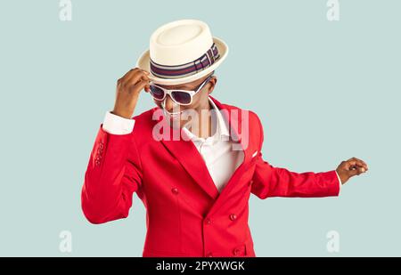 Glücklicher, raffinierter und stilvoller afrikanischer Mann, der Spaß beim Tanzen auf hellblauem Pastellhintergrund hat. Stockfoto