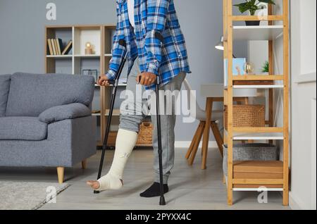 Behinderter junger afrikaner mit gebrochenem Bein, der versucht, mit Krücken zu gehen. Stockfoto