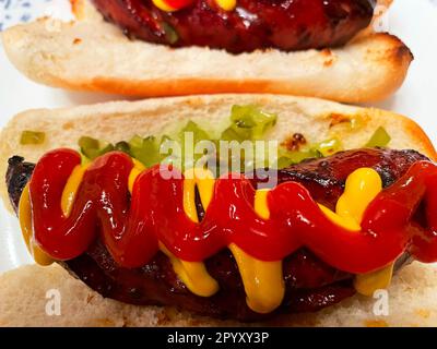 Nahaufnahme einer polnischen Wurst auf einem getoasteten Hotdog-Brötchen mit Ketchup, Senf und Relish. Stockfoto