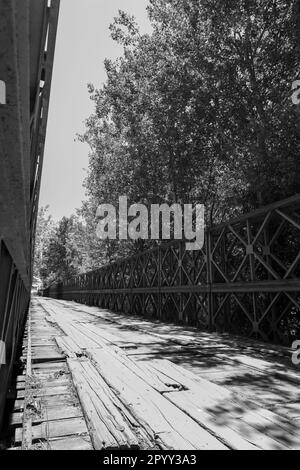 Altmodisch und zeitlos: Eine alte Brücke mit Holzplanken und eisernen Stützen ist ein Zeugnis einer vergangenen Ära Stockfoto