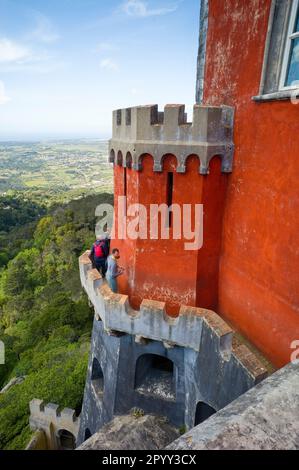 Touristen auf den sehr schmalen und niedrigen Mauern des Pena-Palastes in Sintra, Portugal Stockfoto