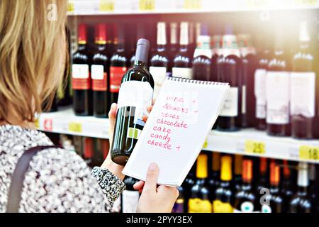 Das Mädchen wählt eine Flasche Wein für ein Date im Laden aus Stockfoto