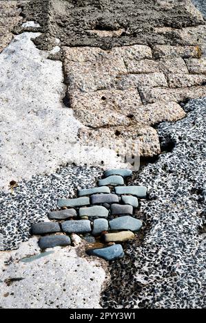Unvollständige Reparaturen an Ufermauern mit verschiedenen Beton- und Pflastersteinen Stockfoto