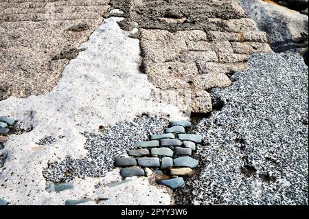 Unvollständige Reparaturen an Ufermauern mit verschiedenen Beton- und Pflastersteinen Stockfoto