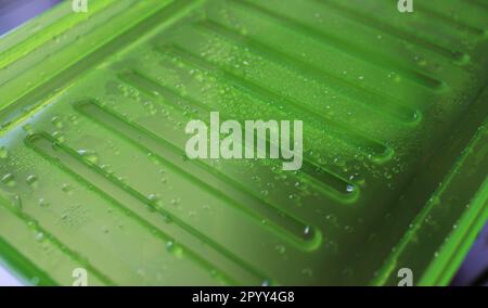 Muster von Kondensattropfen und Wasserbirnen auf einer grünen Kunststoff-Nahansicht Stockfoto