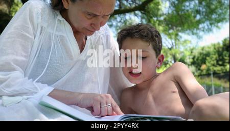 Mutter, die das faule Kind draußen unterrichtet. Eltern helfen dem gelangweilten männlichen Sohn mit Hausaufgaben Stockfoto
