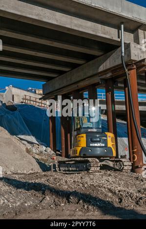 Ein Bagger arbeitet in der Nähe einer im Bau befindlichen Autobahnrampe. Stockfoto