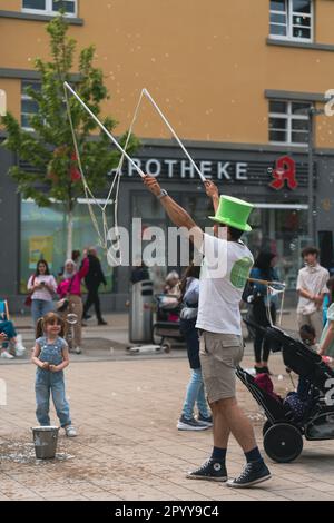 Kaiserslautern, Deutschland. 5. Mai 2023. Ein Straßenkünstler bläst Seifenblasen vor einem entzückenden kleinen Mädchen. Das Street Art Festival findet in der Innenstadt über einen Zeitraum von drei Tagen statt. Die Stadt Kaiserslautern lud internationale Künstler aus 14 Nationen ein. Kredit: Gustav Zygmund/Alamy News Stockfoto