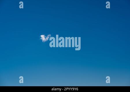 Herzförmige Wolke am blauen Himmel. Stockfoto