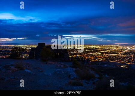 Nachtfoto der Silhouette eines Mannes, der auf dem Dach des Dobbins Lookout steht und die Lichter der Stadt Phoenix beobachtet. Stockfoto