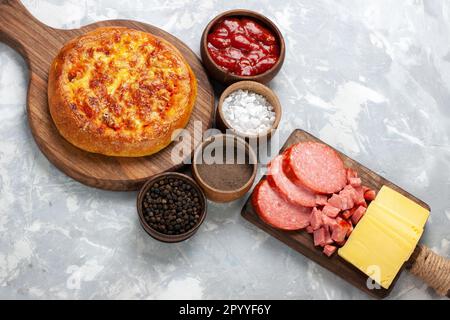 Oben gebackene Pizza mit verschiedenen Gewürzen auf weißem Schreibtisch, Pizza, Teig Stockfoto