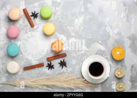Blick auf französische Makronen mit einer Tasse Tee auf einem hellen weißen Tischkuchen, Kekse, Zuckerkuchen und süßem Keks Stockfoto