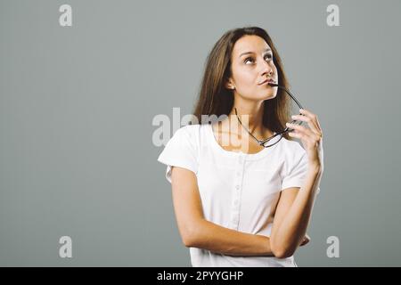 Porträt einer jungen Frau, die denkt und tolle Ideen hat, die Zukunft erfindet, Urlaub und Leben plant. Ihre Fantasie wird mit ihrem Werk dargestellt Stockfoto