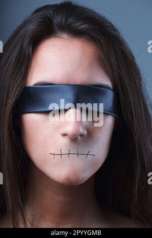 Unheimliches Porträt, Frau mit verbundenen Augen, kein Mund, still. Redefreiheit, Meinungsfreiheit in Diktaturen, Totalitarismus. Demokratie bedeutet dialog Stockfoto