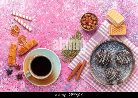 Top View leckere Schokoladenkuchen mit Tee auf pinkfarbenem Hintergrund Kekskuchen süßer Puderzucker Stockfoto