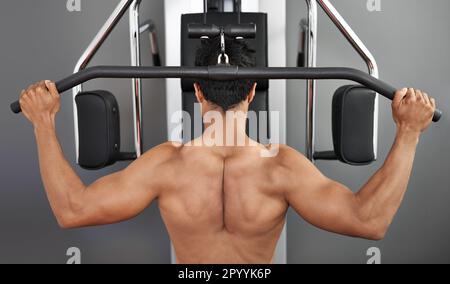 Streben nach GanzkörperFitness. Rückansicht eines jungen ethnischen Mannes, der im Fitnessstudio trainiert. Stockfoto