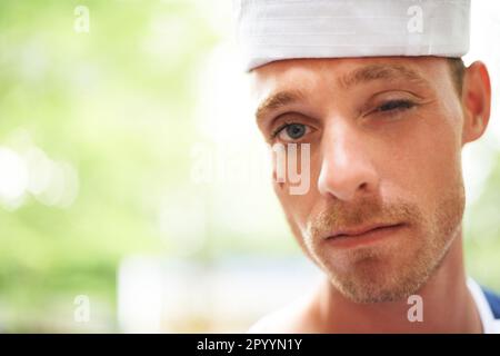 Verspieltes Zwinkern. Ein junger Mann mit weißem Hut, der vor der Kamera zwinkert. Stockfoto
