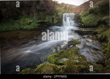 Ein Bach fließt über den Gritstone-Felsen eines kleinen Wasserfalls, der von oben gesehen wird, Kinder Scout, Derbyshire, Peak District Manchester UK Stockfoto
