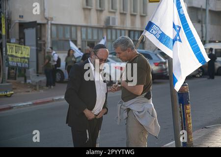 Bnei Brak, Israel. 04. Mai 2023. Ein israelischer Reservist gegen die Reform, die eine israelische Flagge hält, spricht mit einem orthodoxen Mann während eines Protests gegen die Haredi-orthodoxe IDF-Befreiung. Kredit: SOPA Images Limited/Alamy Live News Stockfoto