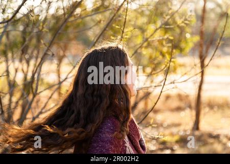 Brünette Frau, die sich im warmen Wintersonnenlicht im ländlichen Australien dreht und Haare fliegt Stockfoto