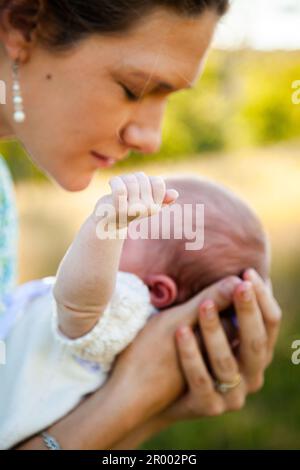 Mutter bückt sich über das Neugeborene, Arm streckt aus Stockfoto