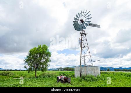 Ein australischer Bauer, der die Windmühle hochklettert, um Reparaturen durchzuführen Stockfoto