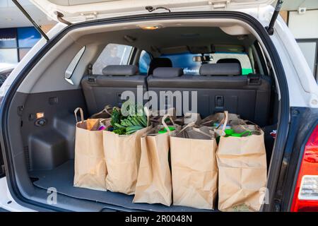 Braune Papiertüten im Kofferraum des Autos voller Lebensmitteleinkäufe von der Direktbestellung bis zur Startbestellung Stockfoto