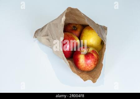 Kleine organische Äpfel in brauner Papiertüte auf weißem Tisch Stockfoto