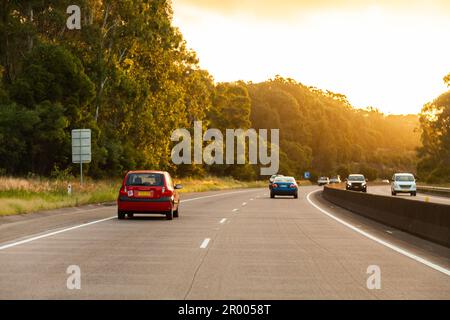 Autos, die bei Sonnenuntergang die Highway Road hinunterfahren, in Hunter Valley, NSW, Australien Stockfoto