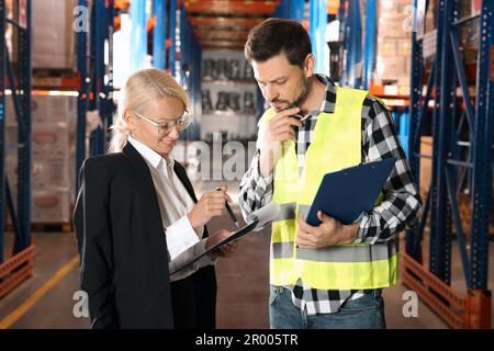 Manager und Arbeiter im Lager mit vielen Produkten Stockfoto