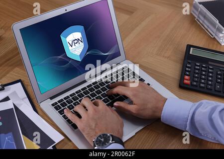 Mann, der ein Laptop mit eingeschaltetem VPN am Tisch benutzt, Nahaufnahme Stockfoto