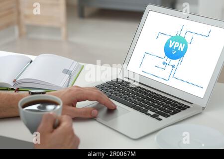 Mann, der ein Notebook mit eingeschaltetem VPN in der Nähe des Schreibtischs verwendet Stockfoto