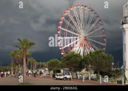 Verschwommener Blick auf das große Riesenrad im Park unter regnerischen Wolken Stockfoto