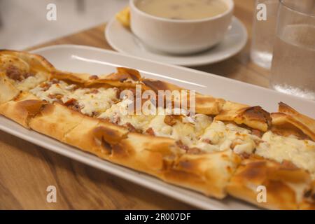 Köstliche Pide auf Holztisch, Nahaufnahme. Traditionelles türkisches Street Food Stockfoto