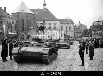 Schwere deutsche Panzer fahren am General Reinhardt am Adolf Hitler Platz vorbei, Komotau (heute Chomutow) in der Tschechoslowakei nach der Annexion des Sudetlands. Nach der Annexion Österreichs verlangte Hitler, dass er in die Region Sudeten der Tschechoslowakei aufgenommen wird. Auf der Münchner Konferenz im September 1938 stimmten die westlichen Mächte dem zu, und die nazis besetzten das Gebiet. Kurz nachdem Hitler sein Versprechen gebrochen hatte und in den Rest der Tschechoslowakei einmarschierte, widmete er sich Polen. Bundesarchiv, Bild 146-1970-050-41/CC-BY-SA 3,0 Stockfoto