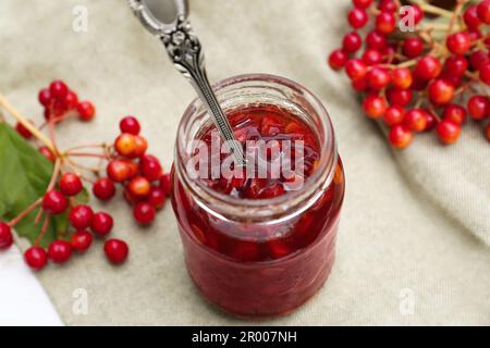 Becher mit Löffel und leckerer Viburnum-Marmelade auf dem Tisch Stockfoto