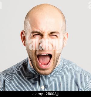 Mir gefällt das überhaupt nicht. Ein gutaussehender junger Mann, der allein im Studio steht und schreit. Stockfoto
